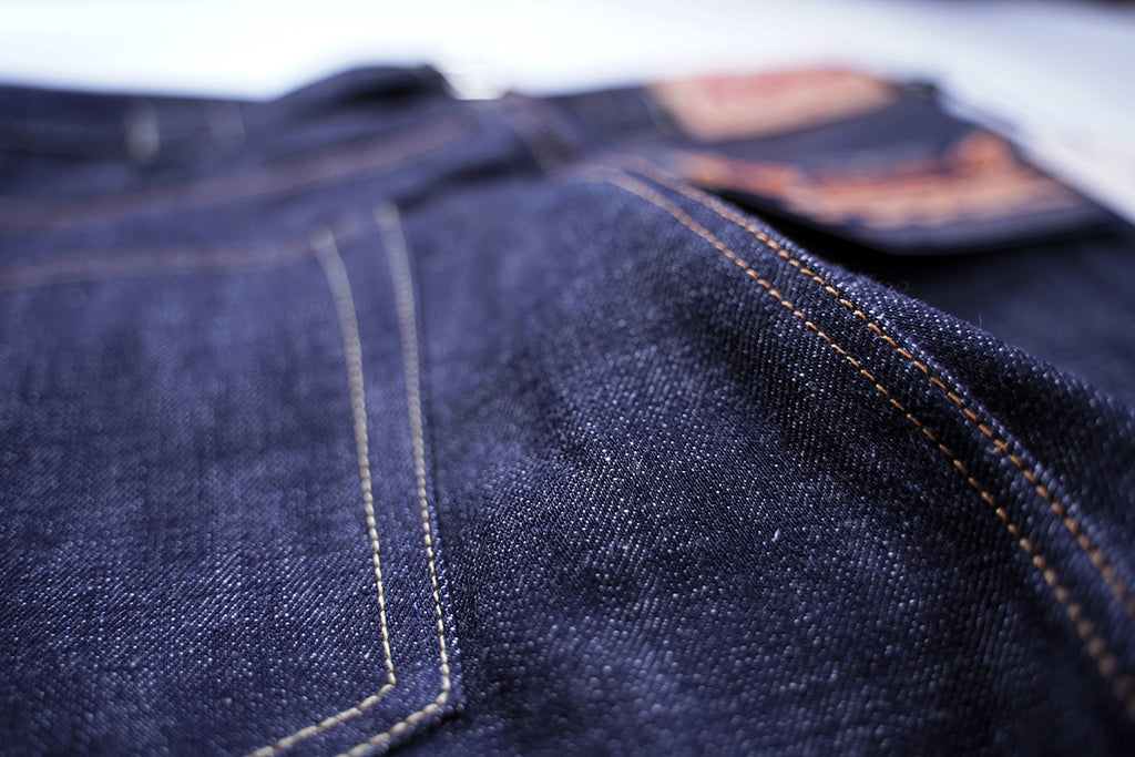 Close-up of back pocket arcuate stitching, tab, and raw denim slub texture on Ancoblack 3700XX