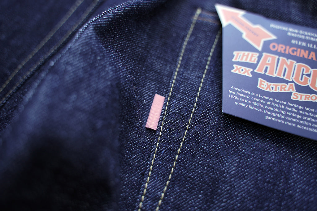 Ancoblack pocket detail showing brand sunfading red tab pocket flasher tag on raw denim